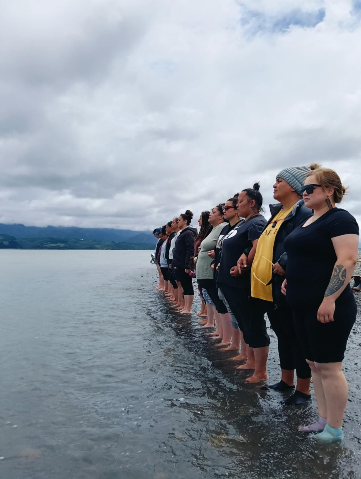 Wāhine standing together at the water during an Ahu Collective wānanga